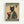 A vintage-style poster featuring a black cat with yellow eyes wearing a traditional Japanese kimono with green fabric and orange floral patterns. The cat holds a red and orange striped coffee cup. Text reads "MORE ESPRESSO" at the top and "LESS DEPRESSO" at the bottom in cream letters on green banners. Japanese characters appear in the upper right corner. The artwork has an aged, beige background with a weathered texture and is displayed in a light wood frame against a white wall.