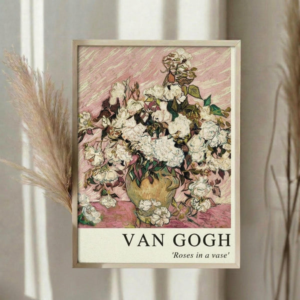 May include: Framed Van Gogh poster print showing white roses in a yellow vase against pink background, displayed on white wall next to dried pampas grass stems. The artwork features thick brushstrokes and vibrant colors typical of Van Gogh's style, with roses and foliage rendered in creamy whites and greens. Light wooden frame surrounds the print, which includes "VAN GOGH" and "Roses in a vase" text at bottom.