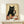 May include: Framed poster print displayed on light wood shelf showing black cat holding wine glass with red wine, surrounded by various cheese wedges on wooden table. Artwork features vintage-style illustration with beige background and warm earth tones. Small white wrapped gift with greenery sits on shelf beside the natural wood frame.