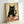 May include: Framed poster print leaning against white wall showing black cat with green eyes holding wine glass filled with red wine, sitting behind wooden table with various cheese wedges including blue cheese and swiss cheese, vintage-style illustration with cream background and warm lighting