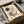 May include: Framed abstract art print in beige, black and burgundy tones featuring geometric shapes, lines, circles and curved forms in Kandinsky's distinctive style. The black-framed artwork sits in an open cardboard shipping box with white tissue paper, alongside wooden dowels used for packaging protection.