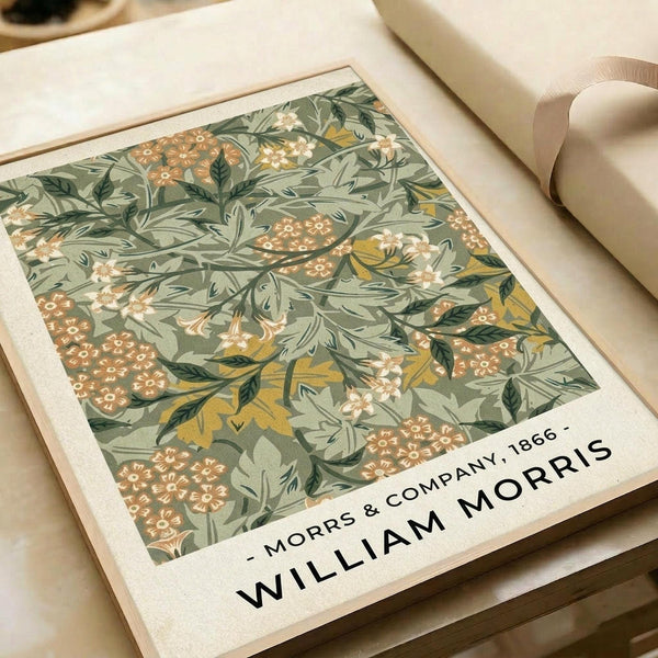 May include: Vintage botanical poster print with intricate green foliage, orange and cream flowers in decorative Arts and Crafts style pattern, displayed in light wood frame on cream colored surface next to neutral fabric roll