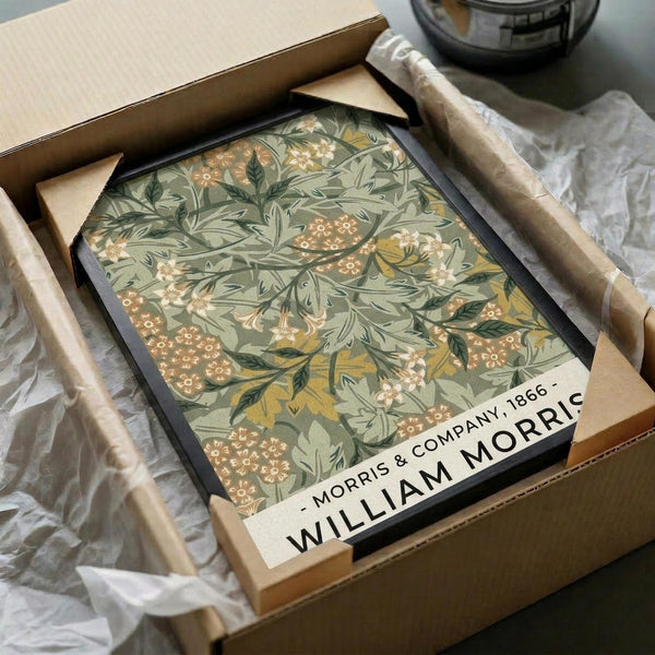 May include: Vintage botanical art print with intricate green foliage, orange and pink flowers in ornate William Morris style pattern, displayed in black frame inside cardboard shipping box with protective tissue paper wrapping on white surface