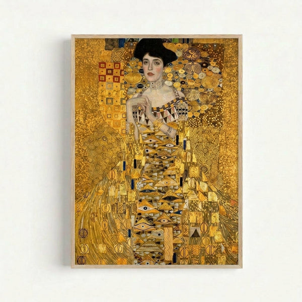 Ornate golden portrait painting of a woman with dark hair in an elaborate patterned dress, surrounded by swirling decorative motifs and geometric designs in rich gold, amber, and bronze tones. The artwork features intricate Art Nouveau styling with spirals, circles, and abstract patterns throughout. Displayed in a simple light wood frame against a white wall.