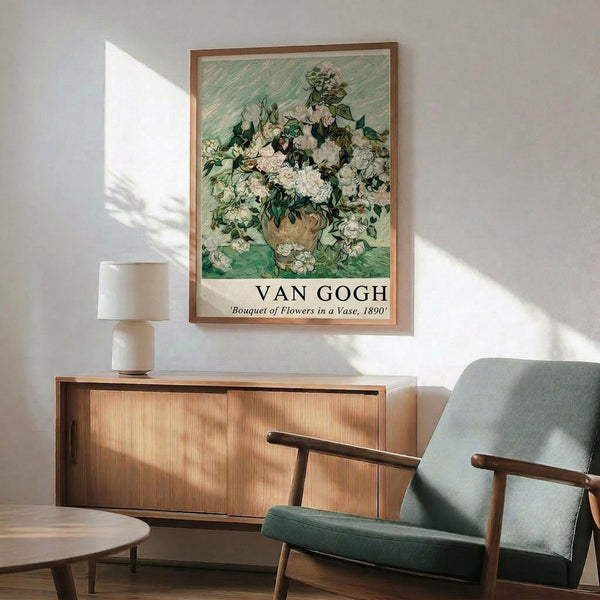 May include: Van Gogh poster print of white roses in brown vase against green brushstroke background, displayed in wooden frame above mid-century modern credenza. Scene shows mint green upholstered armchair with wooden arms, white ceramic lamp, and round coffee table. Warm natural light creates geometric shadows on white wall in minimalist living room setting.