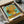 May include: Framed reproduction of van Gogh's iconic sunflowers painting showing yellow blooms in a vase against turquoise background, displayed in black frame within opened cardboard shipping box surrounded by protective white tissue paper on neutral surface.