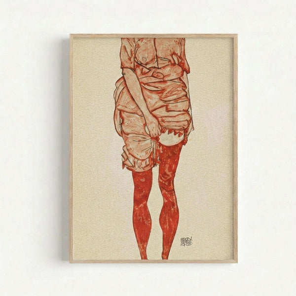 Framed reproduction of an early 20th century expressionist drawing showing the lower torso and legs of a figure in draped fabric clothing. The artwork uses reddish-brown and orange tones on cream paper, with loose, sketchy linework characteristic of the period. The figure wears flowing garments and red stockings or boots. Displayed in a simple light wood frame against a white wall.