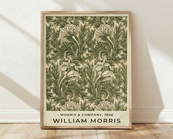 May include: Framed botanical poster print with intricate green acanthus leaf pattern on cream background, displayed in light wood frame against white textured wall. Features ornate Victorian-style flowing foliage design with detailed scrollwork and symmetrical repeating motifs. Natural lighting creates soft shadows on wooden floor beneath the artwork.