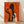 May include: Framed art print with orange textured background showing Art Deco style silhouettes - a large black figure holding a wine glass and a smaller woman with blonde curly hair also holding a glass, displayed in light wood frame against white wall on wooden floor