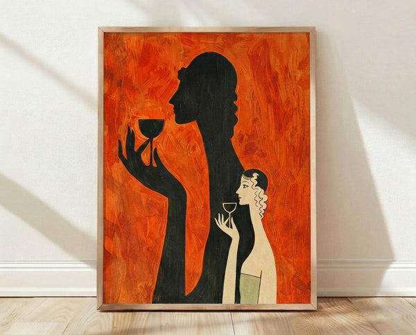 May include: Framed art print with orange textured background showing Art Deco style silhouettes - a large black figure holding a wine glass and a smaller woman with blonde curly hair also holding a glass, displayed in light wood frame against white wall on wooden floor