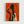 Framed art print with vibrant orange background showing black silhouettes of two figures holding wine glasses. One figure is completely in shadow while the other shows a woman with curly blonde hair in profile, wearing what appears to be 1920s style clothing. The artwork has an Art Deco aesthetic with bold contrasting colors and geometric styling. The piece is displayed in a light wood frame against a white wall.