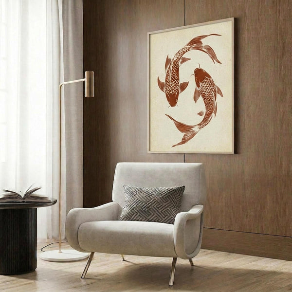 May include: A framed poster featuring two orange-red koi fish arranged in a circular yin yang pattern on cream background, displayed above a beige upholstered armchair with geometric patterned pillow. Modern room setting with wood paneled walls, brass floor lamp, dark round side table with open book, and natural lighting from window with curtains.