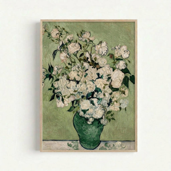 Framed reproduction of Van Gogh's painting showing white roses in a green vase against a pale green background. The artwork displays thick, textured brushstrokes characteristic of Post-Impressionist style. Multiple white blooms with green leaves fill the composition, with a few fallen petals on the surface below the vase. The print is displayed in a simple light wood frame against a white wall.