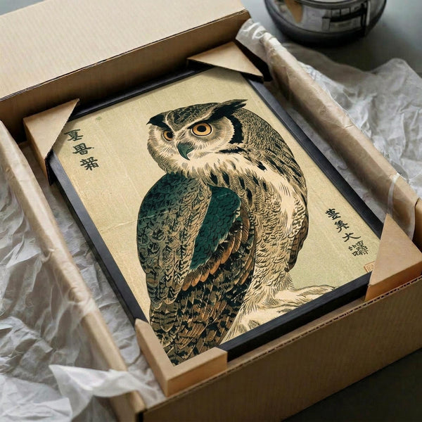 May include: Framed vintage Japanese woodblock print of an owl with detailed brown and green feathers and bright yellow eyes, surrounded by Japanese text. The black-framed artwork sits in an open cardboard box with tissue paper padding, alongside rolled paper tubes on a white surface.