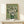 May include: Framed reproduction of Van Gogh's white roses painting in golden wood frame, displayed on light wooden console table against cream wall. Green vase holds abundant white blooms with thick impasto brushstrokes. Small wrapped gift box sits beside frame. Soft natural lighting creates gentle shadows.