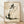 May include: Framed poster print featuring a minimalist ink wash painting of a round, content cat sitting with closed eyes and small smile. Japanese calligraphy characters appear above the cat in black brush strokes. The artwork has a cream background with subtle texture and ink splatters. Natural wood frame sits on light wooden floor against white wall with soft shadows.