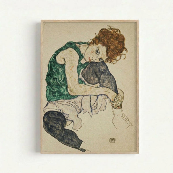 Framed reproduction of an expressionist drawing showing a seated woman with curly reddish hair wearing a green sleeveless top and dark stockings. The figure is rendered in loose, sketchy lines with muted colors against a cream background. The artwork appears in a light wood frame and displays the artist's distinctive angular, emotional style with visible brushstrokes and incomplete areas that fade into the paper.