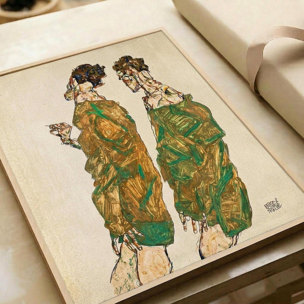 Expressionist artwork showing two elongated figures in flowing green and golden-yellow robes with dark curly hair, drawn in sketchy line style on cream paper. The print is displayed in an open art book or portfolio against white fabric with soft lighting, showing the detailed brushwork and earthy color palette characteristic of early 20th century Austrian art.