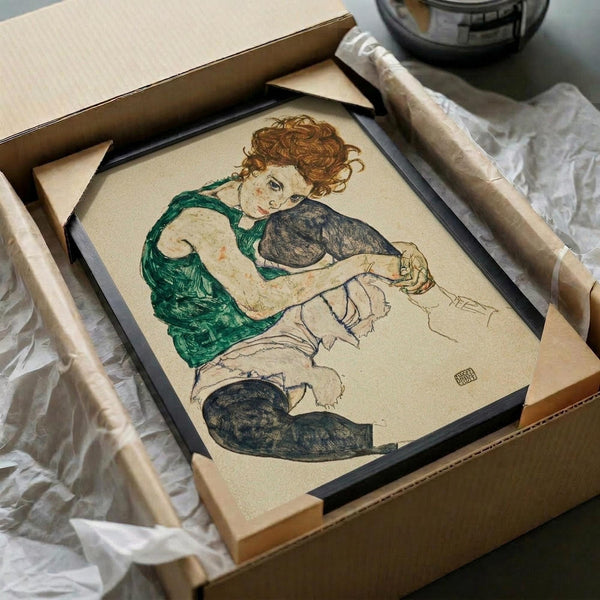 May include: Framed reproduction of an expressionist drawing showing a seated woman with curly auburn hair wearing a green sleeveless top and dark stockings. The artwork features bold outlines and muted colors on cream paper, displayed in a black frame within shipping packaging surrounded by protective materials and cardboard tubes.
