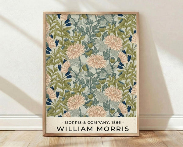 May include: Framed botanical poster print featuring vintage floral pattern with pink chrysanthemums, green foliage, and navy blue accents on cream background. Light wood frame leans against white textured wall above wooden floor with natural sunlight casting shadows across the scene.