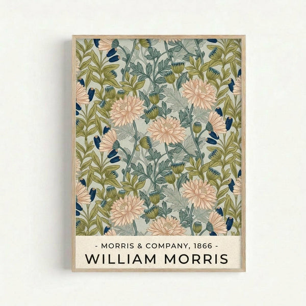 A framed botanical poster featuring William Morris's 1866 chrysanthemum pattern with coral pink flowers, olive green and blue-gray foliage on a cream background. The design shows detailed chrysanthemum blooms and stems in an Arts and Crafts style. Text at bottom reads "Morris & Company, 1866" and "William Morris" in black lettering. The poster is displayed in a thin natural wood frame against a white wall.