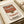 May include: Vintage-style Campbell's tomato soup can poster print displayed in cream matted frame on wooden surface. Red and white retro design with condensed soup label artwork featuring ornate gold seal. Warm beige ribbon visible alongside framed print in styled home setting.
