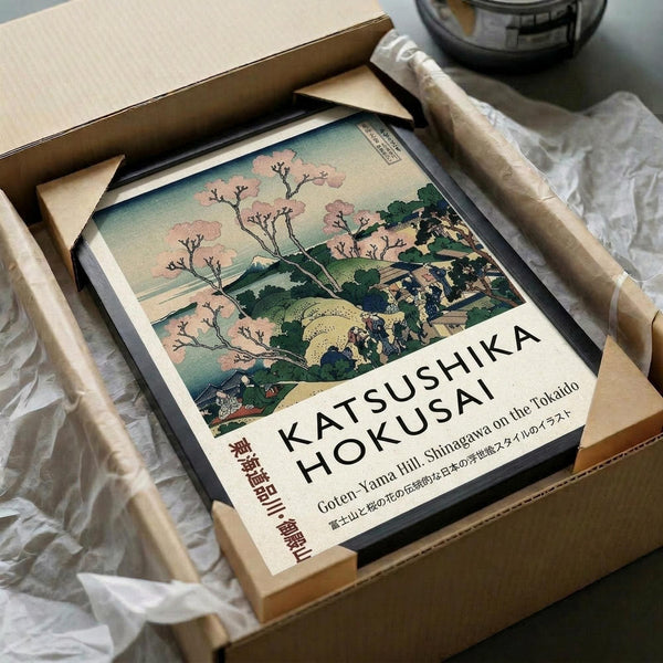 May include: Framed Japanese woodblock print featuring cherry blossoms and Mount Fuji landscape in soft pink, green and blue tones, displayed in wooden shipping box with protective tissue paper. Print shows traditional ukiyo-e art style with delicate flowering branches in foreground and mountain vista background. Wooden frame visible around artwork inside cardboard packaging.