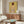 May include: Framed art print featuring a figure with reddish hair viewed from behind against yellow background, displayed on walnut credenza in modern living room with white curved chair, glass coffee table, and white table lamp. Warm natural lighting creates shadows across the minimalist interior space.