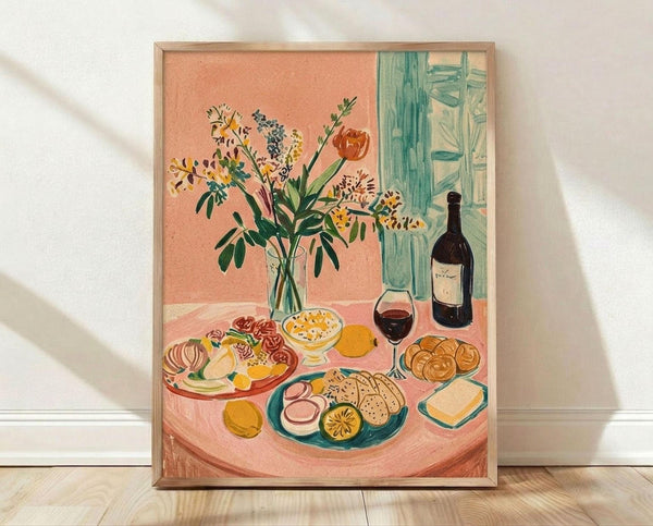 May include: Framed art print leaning against white wall on light wood floor. Artwork shows colorful still life scene with wildflower bouquet in glass vase, wine bottle and glass, assorted foods on plates including bread, cheese, and fruits arranged on peachy pink table. Matisse-inspired style with bold colors, simplified forms, and loose brushwork. Light wood frame, soft natural lighting creates diagonal shadows on textured white wall.