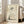 May include: Framed poster print featuring a minimalist ink wash painting of a chubby, sleeping cat in soft gray tones on aged beige paper background, with Japanese calligraphy characters above, displayed in light wood frame leaning against white wall next to beige upholstered chair in bright living room with large windows