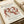 May include: Matisse "The Dance" art print in warm cream tones showing five simplified human figures holding hands in a circle dance. The poster features "MATISSE THE DANCE" at top and "BERGGRUEN & CIE Salon d'Automne Grand Palais des Champs-Élysées, Paris" at bottom. Print sits on neutral fabric surface beside rolled paper, photographed at an angle showing wooden frame edge.