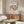 May include: Framed Matisse exhibition poster featuring five red dancing figures in a circle on cream background, displayed above wood credenza in minimalist living room with white curved chair, glass coffee table, and brass floor lamp
