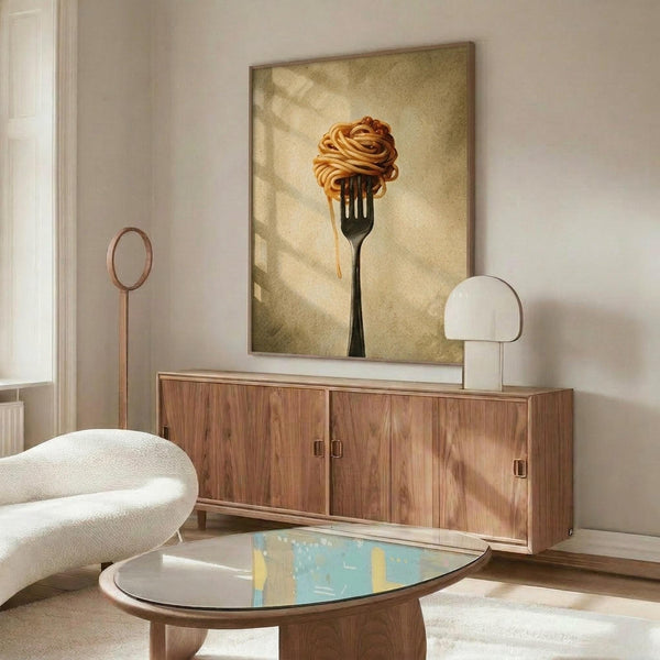 May include: A framed poster artwork showing pasta twirled on a fork against a warm beige background, displayed above a mid-century modern walnut credenza in a contemporary living room. The room features a white curved chair, oval glass coffee table, modern lighting, and neutral tones throughout. Natural sunlight creates soft shadows on the wall.