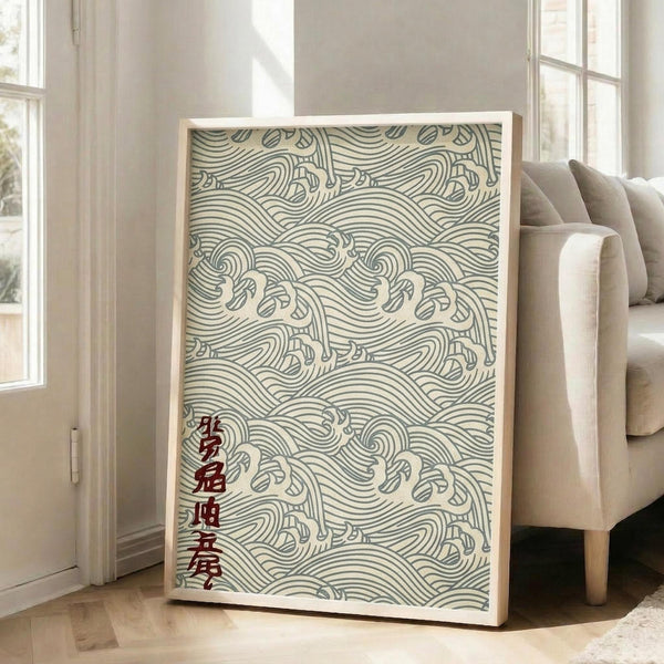 May include: Large framed poster with traditional Japanese wave pattern in teal and cream colors, featuring flowing curved lines and red Japanese characters in bottom left corner. White frame leaning against wall next to beige upholstered chair in bright living room with white walls and windows.