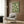 May include: Green wall art print featuring white cranes in flight against sage green background, displayed in modern room setting with beige upholstered armchair, brass floor lamp, and wood paneled wall. Print appears in light wood frame above chair with geometric patterned pillow.
