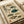 May include: Vintage-style Japanese scientific illustration poster showing seven different pufferfish species in various colors including teal, brown, and yellow-green. The educational chart features detailed fish drawings with Japanese text and red stamp seals on aged beige paper. Shown in a white matted frame laying on a light wooden surface next to rolled white paper, demonstrating the artwork's warm earth tones and traditional scientific diagram aesthetic.