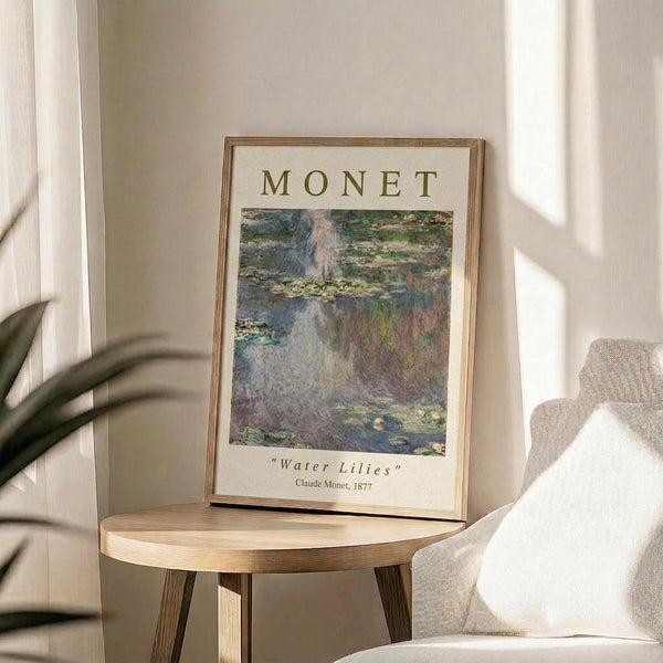 May include: Framed art print featuring Monet's impressionist water lilies painting with soft blues, greens, and pink reflections on water surface. White matted poster with "MONET" text and artwork details displayed on round wooden side table next to beige upholstered chair with throw pillow. Natural sunlight creates shadows on cream wall, with plant leaves visible in corner of bright, minimalist living room setting.