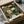 May include: Framed botanical art print featuring William Morris-style design with ornate green foliage and coral-colored flowers on dark background, displayed in black frame inside open cardboard shipping box with protective wrapping paper on white surface