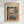 May include: Framed vintage museum poster featuring Henri Matisse's colorful fauve painting of an open window with potted plants on the sill overlooking boats in a harbor. The artwork shows vibrant blues, greens, oranges and pinks in Matisse's distinctive bold style. Natural wood frame mounted on white wall in modern interior setting.