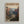 May include: Framed vintage-style travel poster hanging on white wall, featuring Zion National Park canyon landscape with towering red rock cliffs, winding river through green valley floor, and layered mountain ranges under pale sky. Natural wood frame with warm honey finish.