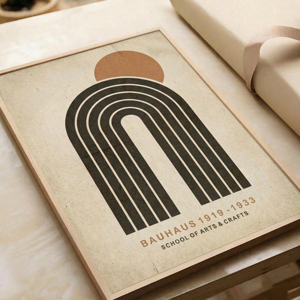 May include: Minimalist poster print featuring a dark green rainbow arch with white stripes and terra cotta sun, displayed on cream textured paper with "BAUHAUS 1919-1933 SCHOOL OF ARTS & CRAFTS" text below. Print sits on neutral fabric surface next to rolled beige paper, showing vintage-inspired geometric design in muted earth tones.