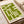 May include: Green and cream geometric abstract art print displayed on a wooden surface next to rolled paper tubes. The minimalist design features bold angular shapes and lines in olive green against a light background, with "bauhaus 1919" text at the bottom. The print appears to be on white paper with clean modern styling.
