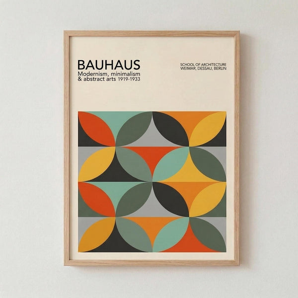 May include: Framed poster with light wood frame hanging on white wall, featuring geometric abstract design with overlapping circles in orange, yellow, mint green, dark green, and gray creating repeating pattern, white background with black Bauhaus text at top referencing the German design school 1919-1933