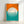 A framed poster featuring a minimalist geometric design with a large white circle representing the sun against a bright orange sky above teal water. Horizontal white lines create a reflection effect across the lower half of the circle. The word "bauhaus" appears vertically in black text on the right side, with "Ausstellung Juli Sept. 1923" in small text along the left margin. The artwork is displayed in a light wood frame against a white wall.