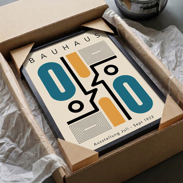 May include: Framed Bauhaus-style poster with geometric design featuring teal numbers "010", orange and black abstract shapes, and concentric square patterns on cream background. The black-framed print is nestled in cardboard packaging with white tissue paper, sitting on a neutral surface next to what appears to be a dark ceramic object.