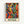 Colorful abstract artwork featuring silhouetted dancing figures in vibrant blues, oranges, greens, and yellows with flowing, organic shapes. The composition shows multiple human forms with raised arms in dynamic movement against swirling colored backgrounds. Below the artwork is green text reading "MATISSE" on a cream background. The print is displayed in a light wooden frame against a white wall.