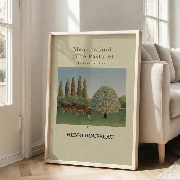 May include: Framed art print of Henri Rousseau's pastoral painting showing cows grazing in a green meadow with tall poplar trees and a large rounded tree, two small figures in the scene. Cream-colored poster with museum-style text layout displayed in light wooden frame, leaning against white wall next to beige upholstered chair in bright, airy room with large windows.