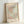 May include: Framed vintage Matisse exhibition poster with abstract cut-out shapes in coral pink, sage green, cream and yellow, featuring black cross-hatched patterns and dotted elements. Light wood frame leans against white wall, casting soft shadows. The artwork shows organic, flowing forms reminiscent of paper cutouts with "MATISSE" and "PAPIERS DÉCOUPÉS" text at top and bottom.