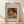 May include: Framed art print of Renoir painting showing young child with reddish-brown hair reading a book, rendered in soft impressionist brushstrokes with warm earth tones. Natural wood frame with cream matting displays against white textured wall on light wooden floor with diagonal shadow patterns.