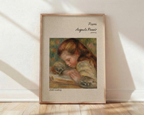 May include: Framed art print of Renoir painting showing young child with reddish-brown hair reading a book, rendered in soft impressionist brushstrokes with warm earth tones. Natural wood frame with cream matting displays against white textured wall on light wooden floor with diagonal shadow patterns.